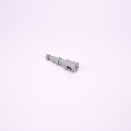 Grå användarpegg med cylindrisk form och flera sektioner med olika diameter. Ena änden är ihålig med ett avlångt spår, medan den motsatta änden har en räfflad yta.