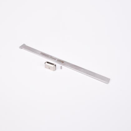 Tre metall komponenter: Ett rektangulärt metallföremål med kvadratiska sektioner och hål i ena änden, samt en liten rektangulär metallbit och en cylindrisk pinne.