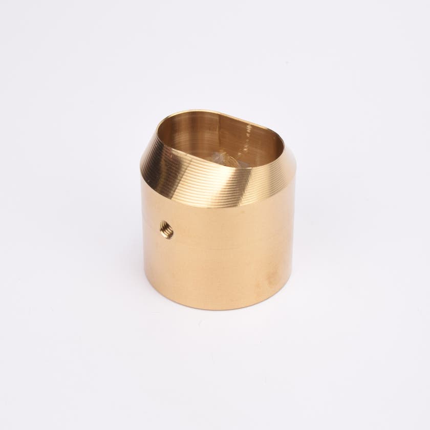 Mässingsfärgat utfyllnadsadapter i metall med snedskuren topp som bildar en oval öppning.