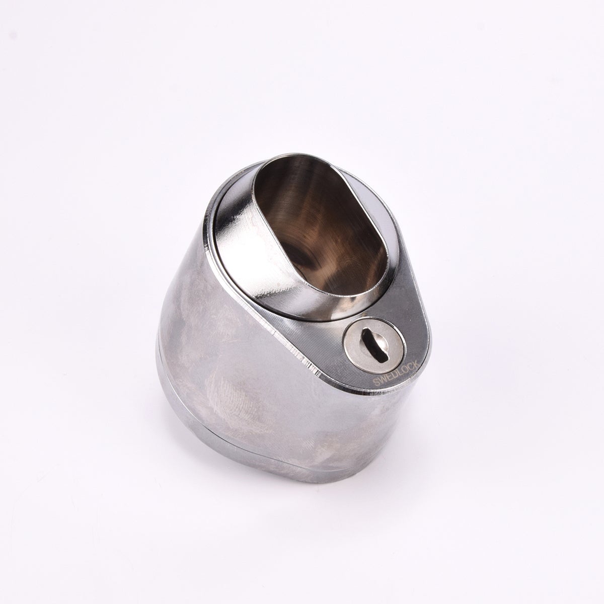 Droppformat metallhus med ovalt urtag för låscylinder, samt nyckelhål i nedre avsmalnande delen.