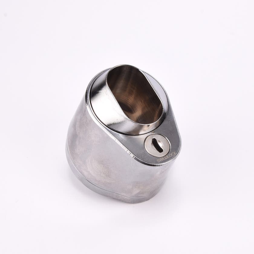 Droppformat metallhus med ovalt urtag för låscylinder, samt nyckelhål i nedre avsmalnande delen.