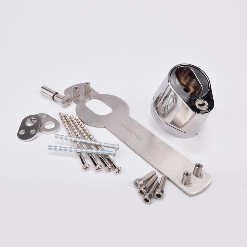 Monteringssats för lås med kromad låshusdel, metallplatta och skruvar.