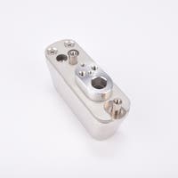 Rektangulär metallkomponent med flera gängade hål och monteringsfästen.